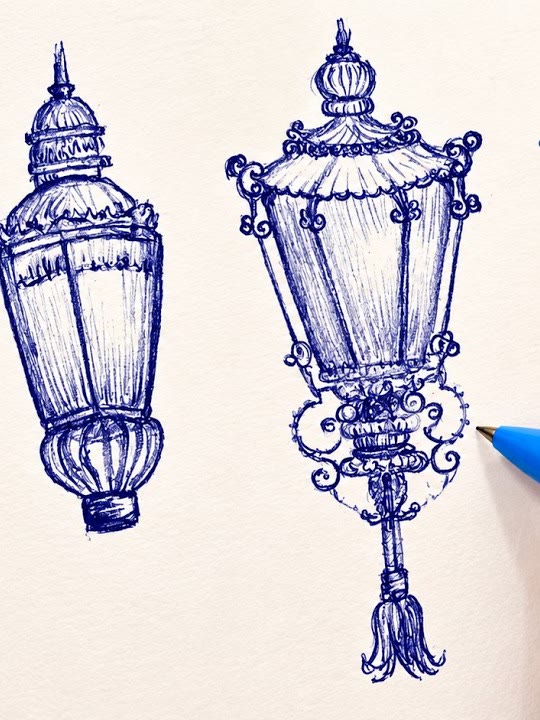 Blue ballpoint pen drawing of two ornate street lanterns with cross-hatched glass panels and curling metal scrollwork, by Marah Maitale Art