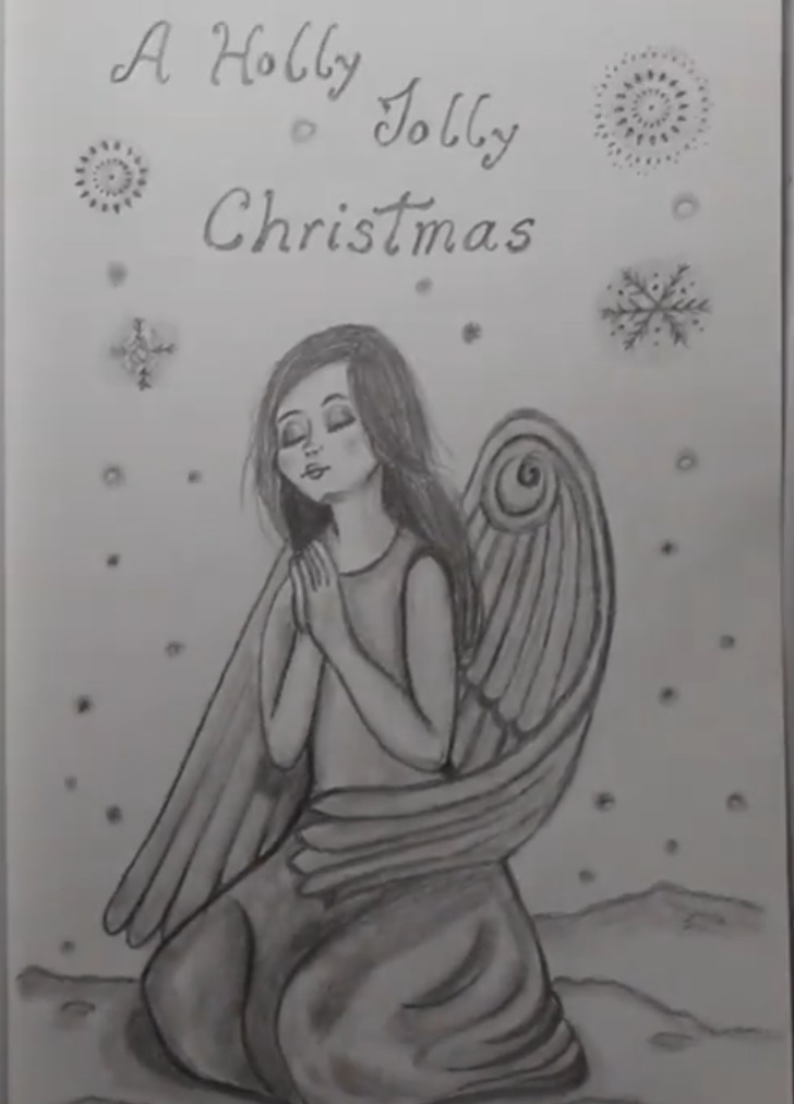 Graphite pencil drawing of a kneeling angel with long hair, closed eyes, folded hands and large feathered wings, with the words A Holly Jolly Christmas, snowflakes and ornaments on a sketchbook page