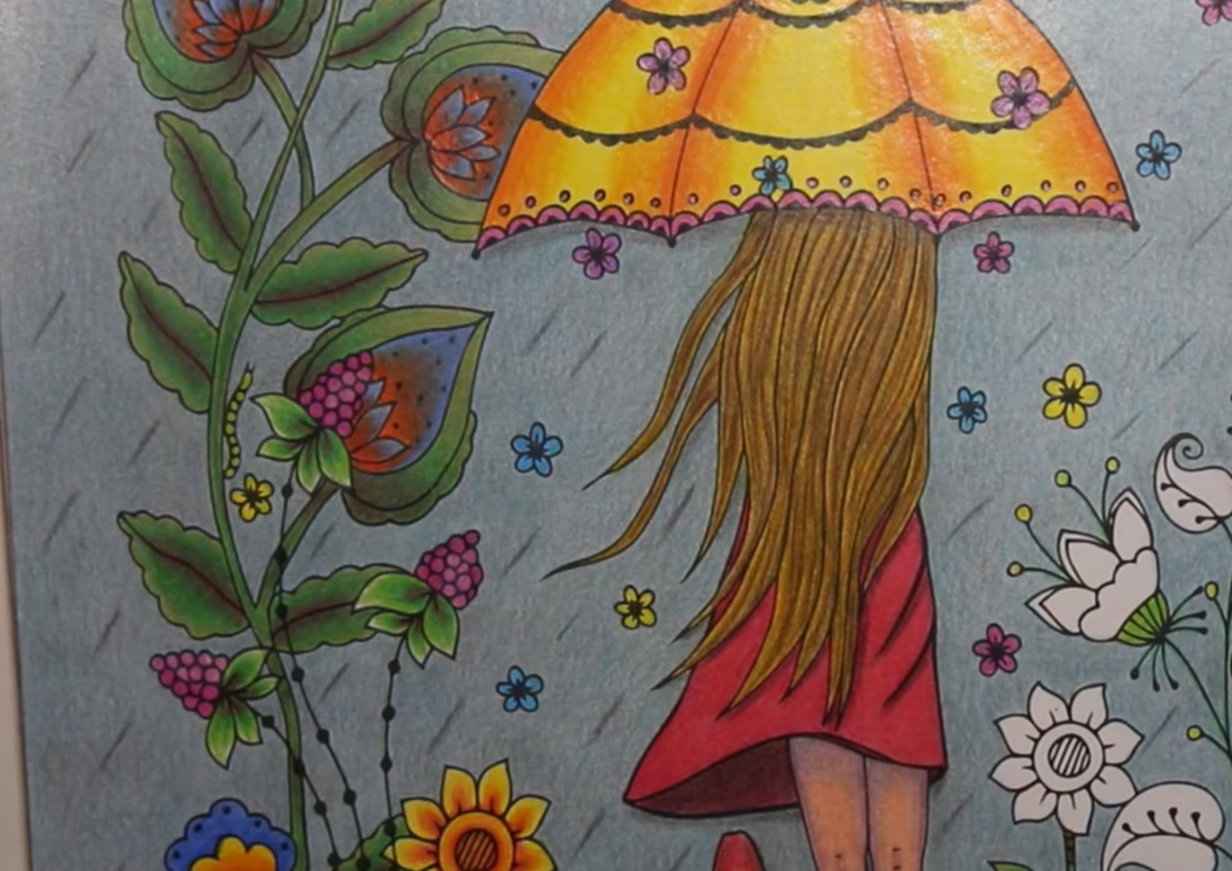 Colored page from Fantasia Color: a girl with long blonde hair and a red dress under a big yellow umbrella in the rain, with green vines, red and blue teardrop flowers, raspberries, a sunflower and a few white flowers still uncolored on the right