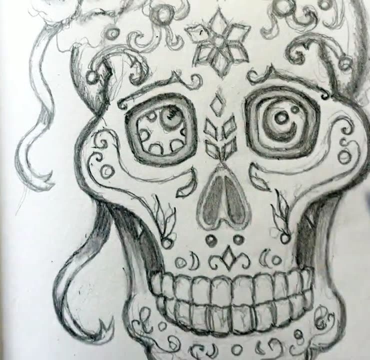 Graphite pencil drawing of a decorated Day of the Dead sugar skull with swirls, a flower on the forehead and flowing ribbons, in a sketchbook