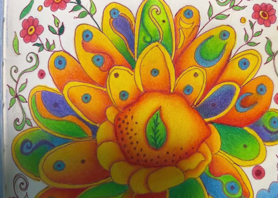 Folk-art style flower page with a large orange flower, blue blossoms and green leaves being colored with Derwent Coloursoft pencils in a sketchbook